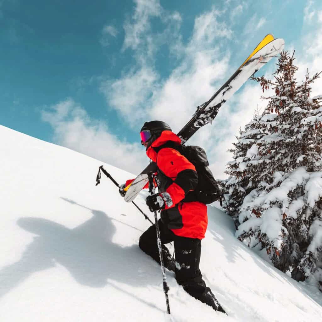 Escursionista con sci da alpinismo invernale su neve alta in montagna, abbigliamento da sci tecnico e attrezzatura outdoor.