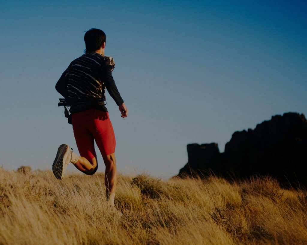 Runner su crinale erboso al tramonto con scarpe KEEN da trail