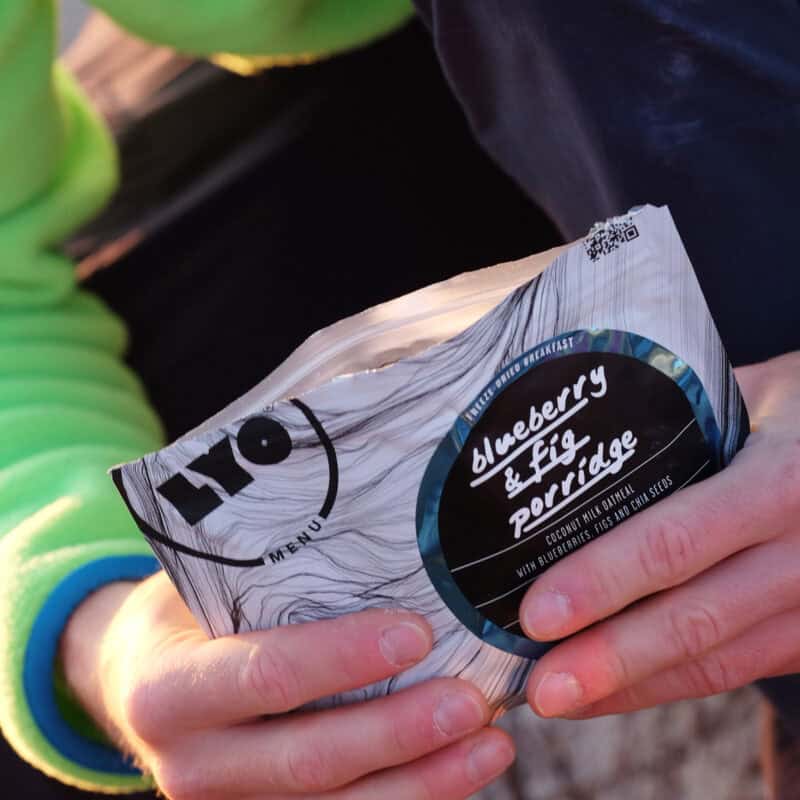 Busta Lyofood Blueberry & Fig Porridge tenuta in mano dal tester durante la colazione outdoor